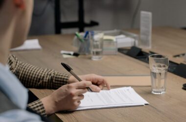 service-1 Person in business attire signing a document at a wooden table in an office setting.